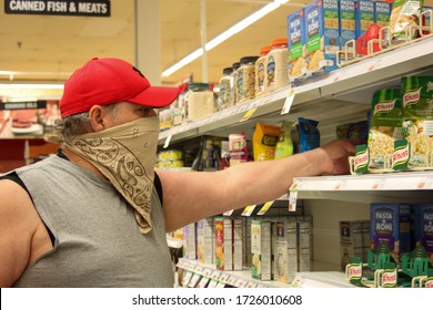 Middletown, NY / USA - 05/04/2020: Man Shopping In Price Chopper Grocery Store Wearing Bandanna As Protective Face Mask During COVID-19 Coronavirus Pandemic, Reaching For Shelf Stable Essentials Food