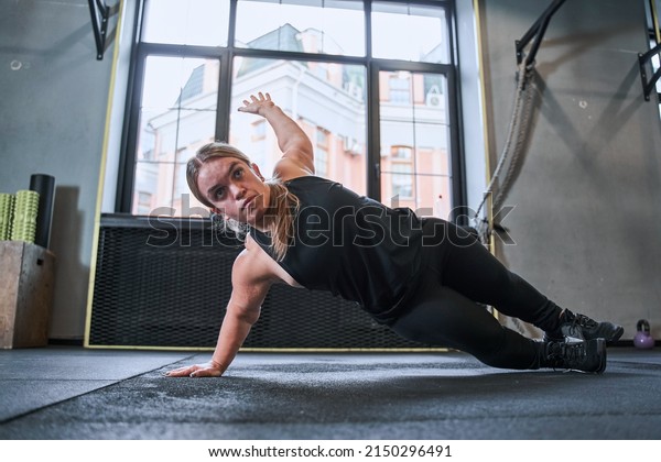 Midget\
woman standing in side plank, training at the\
gym