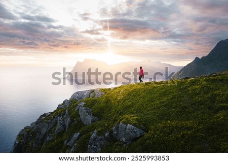 Similar – Man sitting on a cliff of a fjord with low sun on the European Arctic Ocean