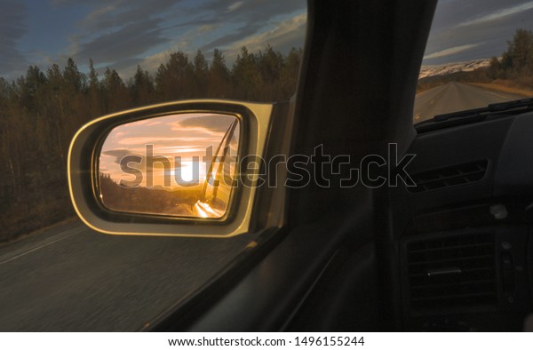 Midnight sun in the\
side mirror driving over \