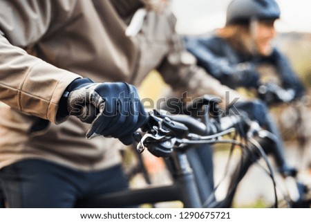 A midsection of active senior couple with electrobikes cycling outdoors.
