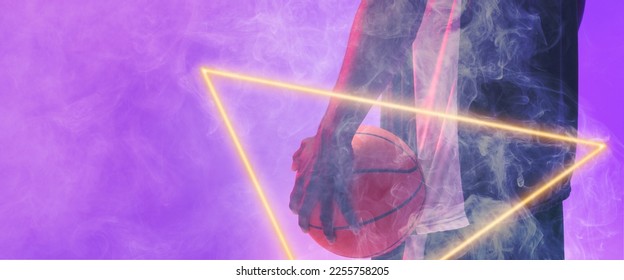 Midsection of african american basketball player with ball and glowing triangle on purple background. Hand, copy space, composite, illuminated, sport, competition, illustration, shape and smoke. - Powered by Shutterstock