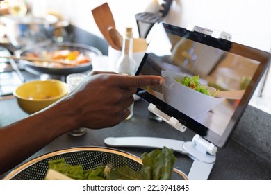 Midsection Of African American Man Cooking Dinner In Kitchen, Using Tablet. Spending Quality Time At Home Alone.