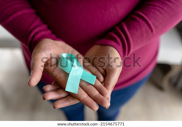 Midsection of african american\
mid adult woman with prostate cancer awareness blue ribbon.\
unaltered, cancer, healthcare and medicine and social awareness\
symbol concept.