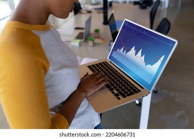 Midsection Of African American Woman In Office Using Laptop With Graphs On Blue Screen. Business Communication, Inclusivity, Flexible Working, Data And Digital Interface Concept.