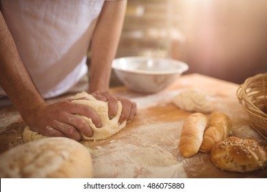 Mid-section of baker kneading a dough in bakery shop - Powered by Shutterstock