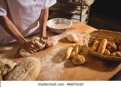 Mid-section of baker kneading a dough in bakery shop - Powered by Shutterstock