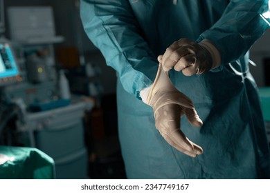 Midsection of biracial male surgeon wearing surgical gown and gloves in operating theatre. Hospital, surgery, hygiene, medicine, healthcare and work. - Powered by Shutterstock