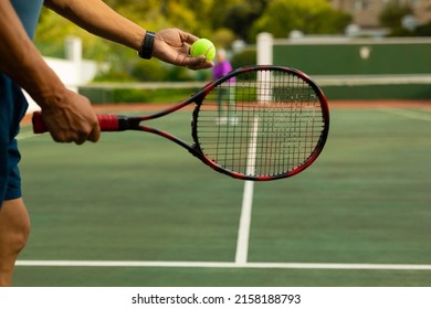 Midsection of biracial senior man holding racket serving tennis ball while playing at tennis court. unaltered, sport, competition, retirement, healthy and active lifestyle concept. - Powered by Shutterstock