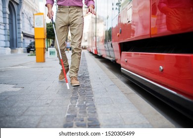 Midsection of blind man with white cane getting on public transport in city. - Powered by Shutterstock