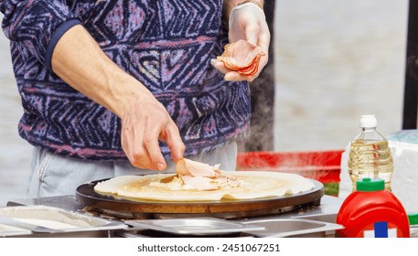 The midsection body of a chef preparing crepes, French pancakes with ham and cheese at farmers market stall in Prague Naplavka, Czech Republic - Powered by Shutterstock