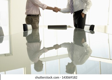 Midsection Of Business People Shaking Hands In Conference Room