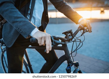Midsection of businessman commuter with electric bicycle traveling from work in city. - Powered by Shutterstock