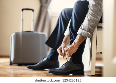 Midsection of businessman on a business trip sitting in a hotel room, tying shoelaces. - Powered by Shutterstock