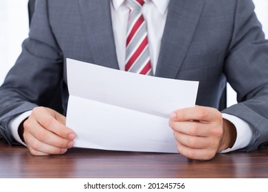 Midsection of businessman reading document at desk - Shutterstock ID 201245756