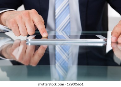 Midsection of businessman using digital tablet at desk in office