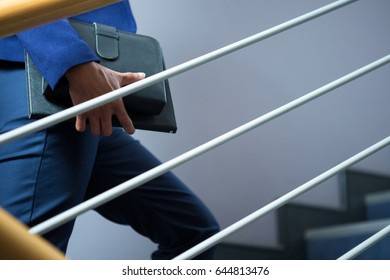 Mid-section of businesswoman with diary climbing up the stairs - Powered by Shutterstock