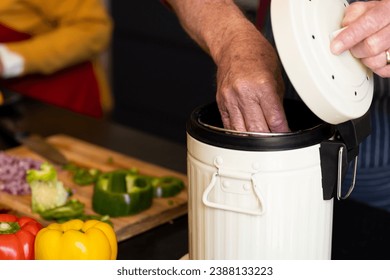 Midsection of caucasian senior man preparing food, composting vegetable waste in kitchen. Ecology, recycling, retirement, cooking, healthy eating, domestic life and senior lifestyle, unaltered. - Powered by Shutterstock