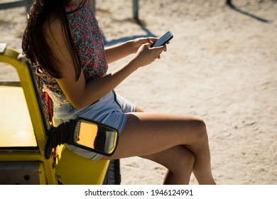 Midsection of caucasian woman sitting on beach buggy by the sea using smartphone. beach break on summer holiday road trip. - Powered by Shutterstock