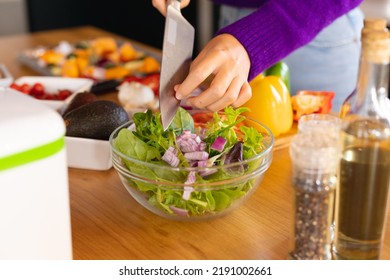 Midsection of caucasian woman standing in kitchen preparing salad. Domestic life, food and healthy eating, spending time alone at home. - Powered by Shutterstock