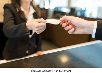 Midsection Of Clerk Giving Card Key To Business Professional At Front Desk In Hotel