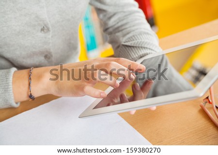 Midsection closeup of female student using digital tablet in college library