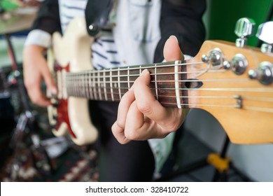 Midsection closeup of woman playing guitar in recording studio - Powered by Shutterstock