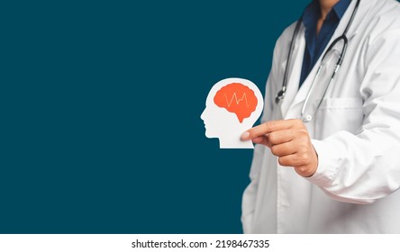 Midsection of doctor in uniform holding a white head with a red brain symbol made from paper while standing on a blue background. Space for text. Medical and healthcare concept - Shutterstock ID 2198467335