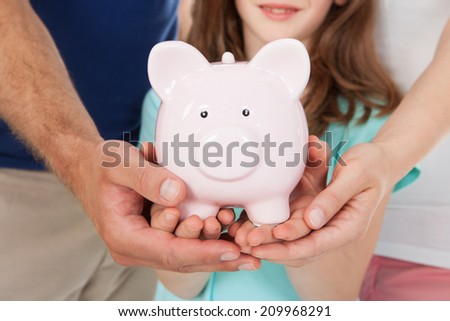 Midsection of family holding piggy bank together