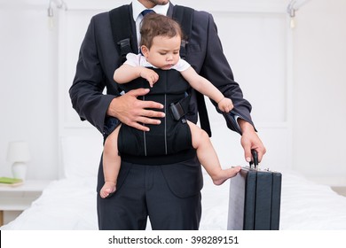 Midsection of father carrying baby while holding briefcase at home - Powered by Shutterstock