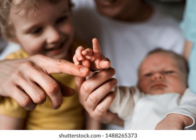 Midsection of father with newborn baby and small toddler son at home.