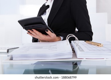 Midsection of female accountant calculating tax at desk in office
