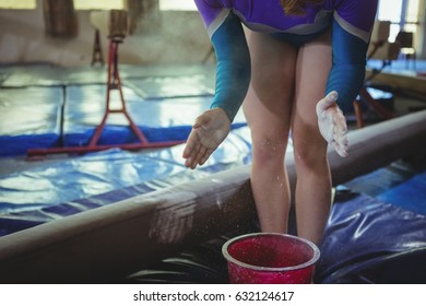Mid-section of a female gymnast applying chalk powder on her hands before practicing - Powered by Shutterstock