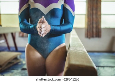 Mid-section of a female gymnast rubbing her hands with chalk powder - Powered by Shutterstock