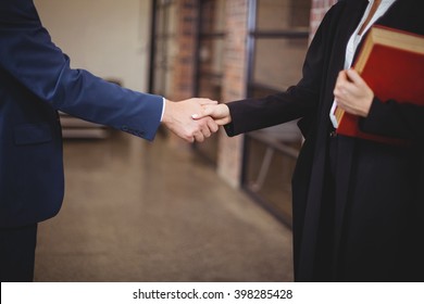 Midsection of female lawyer handshaking with client while standing in office - Powered by Shutterstock