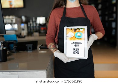 Midsection Of Female Staff Showing Contactless Menu QR Code On Digital Tablet In Restaurant