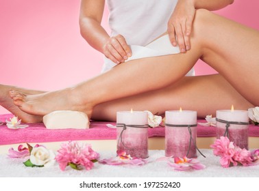 Midsection Of Female Therapist Waxing Customer's Leg At Beauty Spa