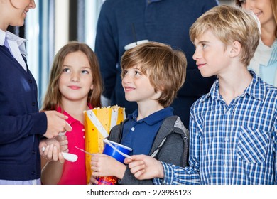 Midsection Of Female Worker Checking Movie Tickets Of Family At Cinema