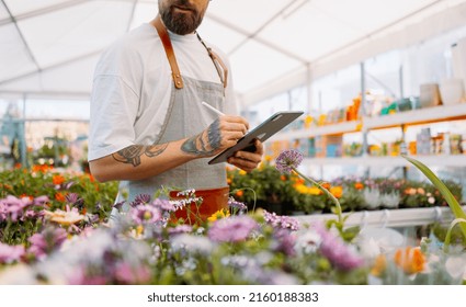 Midsection Of Gardener Using Tablet In Garden Centre.