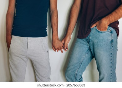 midsection of gay couple hand in hand against white wall  - Powered by Shutterstock