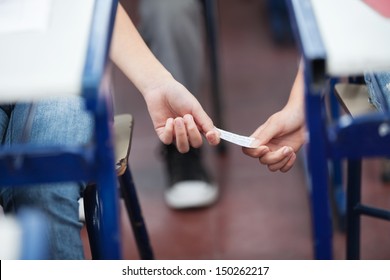 Midsection of girl giving cheat sheet to boy during examination in classroom - Powered by Shutterstock