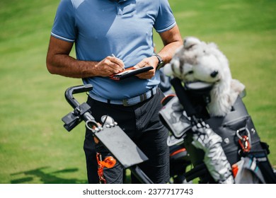 Midsection of golfer writing on score card standing at golf course concept - Powered by Shutterstock