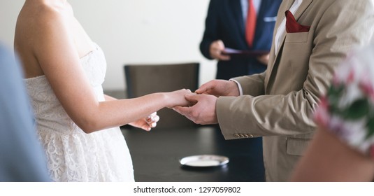 The midsection of the groom wears the bride's ring during the wedding ceremony