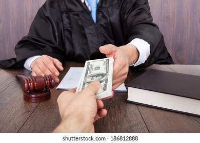 Midsection of judge taking bribe from client at desk in courtroom - Shutterstock ID 186812888