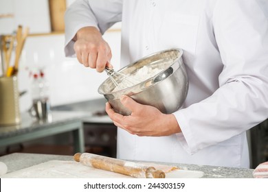 Midsection Of Male Chef Mixing Batter With Wire Whisk In Bowl At Commercial Kitchen Counter