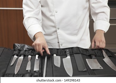 Midsection of male chef selecting knife sharpener out of full set in commercial kitchen - Powered by Shutterstock