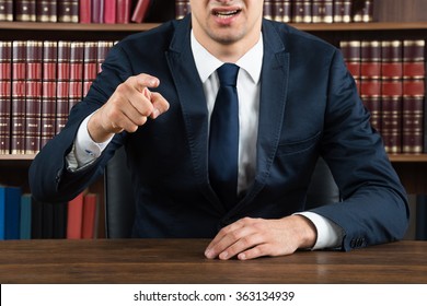 Midsection Of Male Lawyer Arguing While Sitting At Desk In Courtroom