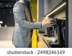 Midsection of male project manager preparing coffee with coffeemaker while working in modern office