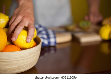 Mid-section of male staff picking a lemon fruit from a bowl in supermarket - Powered by Shutterstock