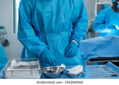 Midsection of male surgeon wearing protective clothing in operating theatre. medicine, health and healthcare services during covid 19 coronavirus pandemic. - Shutterstock ID 1962040363